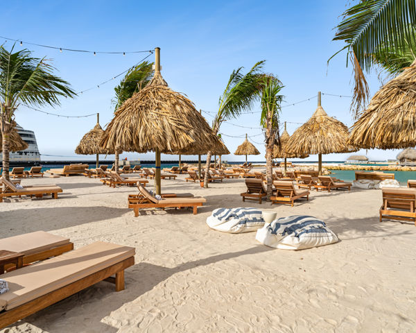 Privéstrand met palapas en palmbomen bij The Rif